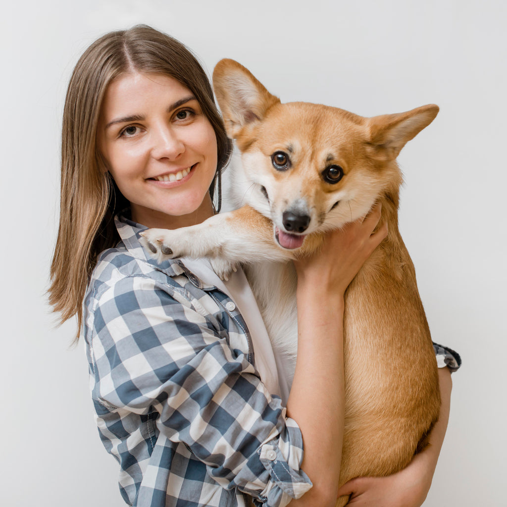 Duena sonriente sosteniendo a su perro de cerca
